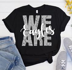 we are eagles t - shirt on top of a pair of jeans and shoes next to flowers