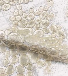 a white and gold lace fabric with flowers on the bottom, along with beaded sequins