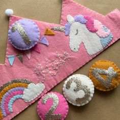 two felt unicorns are sitting next to each other on a piece of pink material