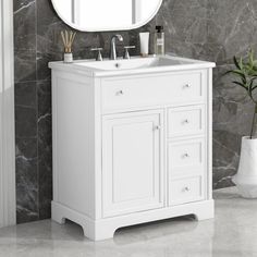 a white bathroom vanity with a round mirror above it and a plant in the corner