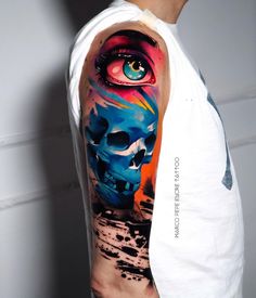 a man's arm with a colorful skull and eye tattoo on the upper half of his arm