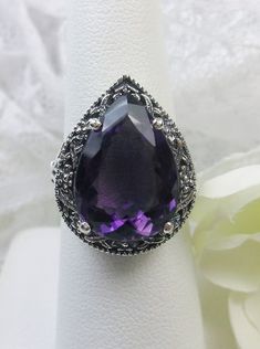 Natural Amethyst Gemstone Teardrop RingTear Vic Design#D28 Inspired by Victorian and Art Deco designs, this high-quality filigree ring is handcrafted in sterling silver. This teardrop ring is set with an 8.37 carat pear cut flawless natural purple amethyst gemstone. The gem is 16mm (~5/8") x 12mm (~1/2"). The gorgeous stones have lovely vibrant color. The inside of the band is marked 925 for sterling silver. Notice the beautiful filigree of the silver setting. This is a ring with beauty and grac Teardrop Amethyst Ring For Formal Occasions, Elegant Silver Teardrop Amethyst Ring, Elegant Teardrop Amethyst Gemstone Ring, Elegant Teardrop Amethyst Ring For Formal Occasions, Teardrop Amethyst Ring For Anniversary, Elegant Teardrop Amethyst Ring, Purple Amethyst Teardrop Ring, Teardrop Amethyst Ring For Gift, Elegant Teardrop Amethyst Ring Gift