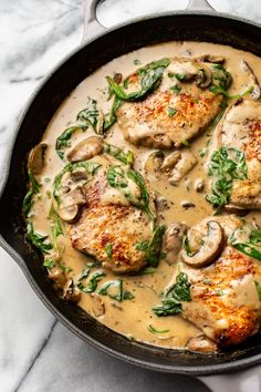 chicken with mushroom sauce and spinach in a skillet on a marble countertop