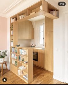 an open book shelf in the middle of a room with wooden floors and pink walls