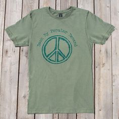 It is all about supply and demand, right? So, Back By Popular Demand, we give you this peaceful t shirt. Printed on an ultra soft, 100% cotton tee, is the phrase "Back by Popular Demand" written above a distressed peace sign. Go forth and wear in peace. Cotton Short Sleeve T-shirt With Peace Sign, Hippie Style Summer Streetwear T-shirt, Summer Hippie Streetwear T-shirt, Hippie Cotton T-shirt For Streetwear, Eco-friendly Graphic Print T-shirt For Summer, Eco-friendly Crew Neck Tops For Summer, Hippie Cotton Tops For Streetwear, Hippie Soft-washed Cotton T-shirt, Hippie Style Screen Print T-shirt