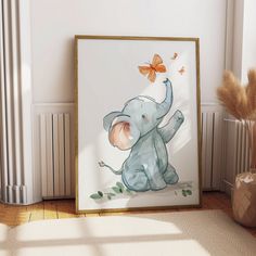 an elephant with a butterfly on its head is sitting in front of a framed painting