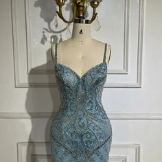 Exquisite evening gown in a stunning blue hue, perfect for upscale events. Features elegant spaghetti straps for a sophisticated and modern look. Adorned with luxurious feather and bead embellishments for added opulence and glamour. Crafted with meticulous attention to detail and high-quality materials for a luxurious feel. Inspired by Dubai luxury fashion, designed to exude elegance and refinement. Ideal attire for women attending weddings, formal events, or upscale parties. Flattering fit that Blue Gala Gown With Spaghetti Straps, Blue Spaghetti Strap Gown For Gala, Elegant Blue Gown With Spaghetti Straps, Blue Spaghetti Strap Prom Evening Dress, Blue Spaghetti Strap Evening Dress For Prom, Glamorous Blue Evening Dress With Spaghetti Straps, Blue Spaghetti Straps Evening Dress For Gala, Gala Evening Dress With Spaghetti Beaded Straps, Evening Dress With Beaded Spaghetti Straps For Gala