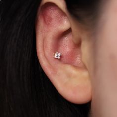 a woman's ear is shown with a single diamond in the middle and two smaller diamonds at the bottom