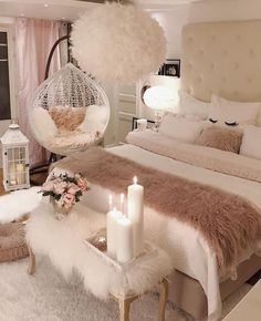 a bedroom with a large bed and white fur on the headboard, two candles in front of the bed