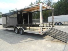 an enclosed trailer parked in a parking lot with the door open and ramp attached to it