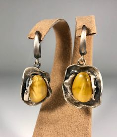 Enhance your style with our Handmade Earrings, featuring light yellow amber set in textured 925 sterling silver. These exquisite earrings are designed for women who appreciate original and unique jewelry. The light yellow amber stones are beautifully complemented by the textured silver, creating a stunning and eye-catching piece that adds a touch of elegance and sophistication to any outfit. Product Details: Material: 925 Sterling Silver Stone: Light Yellow Amber Design: Textured Silver with Uni Modern Amber Drop Earrings, Modern Yellow Jewelry With Polished Finish, Modern Polished Yellow Jewelry, Modern Yellow Baltic Amber Jewelry, Modern Yellow Nickel-free Jewelry, Unique Polished Drop Earrings, Elegant Yellow Earrings With Polished Finish, Elegant Yellow Metal Earrings, Unique Round Earrings With Polished Finish