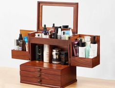 an open wooden box containing various items on top of a table next to a mirror