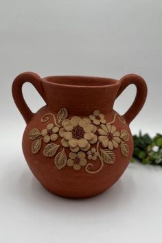 a brown vase with flowers painted on it