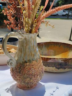 a vase filled with flowers sitting on top of a table next to other plates and bowls