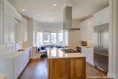 a large kitchen with white cabinets and wood floors