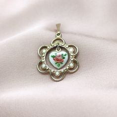 "Lovely vintage gilt sterling silver pendant, made by renowned Norwegian jewellery maker Finn Jensen. Pendant is designed as ornate and enamel adorned round outer part with lovely heart shaped dangle in the middle. Tiny dancing dangle features small rose flower painted on the silver white guilloche enamel background. Finn Jensen began his career in 1944, in partnership at Jensen & Aamodt workshop, and in 1953, he became the sole owner of his Finn Jensen company, as an independent manufacturer of Victorian Enamel Yellow Gold Necklace, Victorian Yellow Gold Enamel Necklace, Victorian Style Yellow Gold Enamel Necklace, Antique Enamel Jewelry For Anniversary, Enamel Locket Jewelry For Anniversary, Elegant Enamel Heart Pendant Jewelry, Victorian Gold Enamel Necklace, Victorian Round Enamel Jewelry, Antique Enamel Round Pendant Jewelry