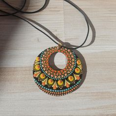 a wooden necklace with an orange and blue design on it, sitting on a table