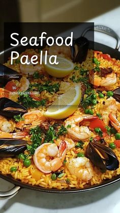 seafood paella in a skillet with lemon wedges