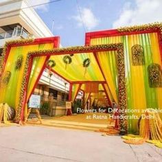 an outdoor wedding venue decorated with yellow and green draping, flowers and greenery