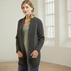 a woman standing in an empty room wearing a cardigan