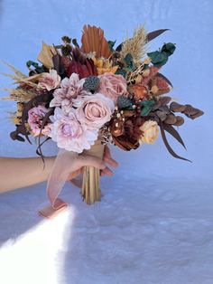 a bouquet of flowers is being held by someone's hand on a white background