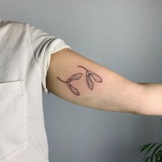 a person with a tattoo on their arm that has leaves coming out of the back