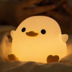 a small light that looks like a ducky sitting on top of a bed with its eyes open