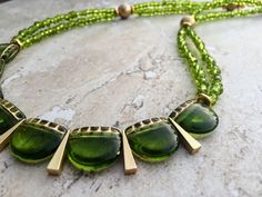 This delicately gorgeous necklace features a bib made using Czech glass beads in fresh green with gold accents interspersed with matte gold finish made-in-USA triangle charms. The length of the necklace is made using two strands of translucent Czech seed beads, Tierracast gold nugget discs and matte gold Czech glass beads.  The necklace measures approx. 22 inches from end to end and closes in a gold plated lobster clasp with an easy to hook big ring.  Free shipping within US. Green Necklace, Gold Necklace Dainty Necklace Seed Bead Necklace Boho Chic Hippie Necklace Boho Necklace 21st Birthday Gift For Her Mom Gift