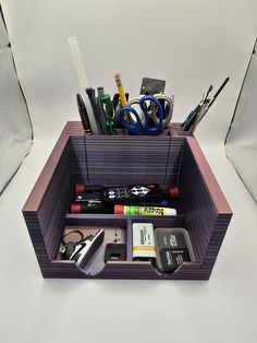 a desk organizer with pens, scissors and other office supplies in it on a white surface