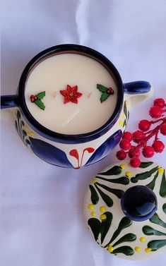 a cup of milk next to a donut with holly decorations on it and a candle holder