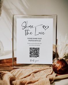 a photo frame sitting on top of a table next to a vase with feathers in it