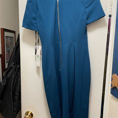 a blue jumpsuit hanging on a wall next to a door with a black handbag