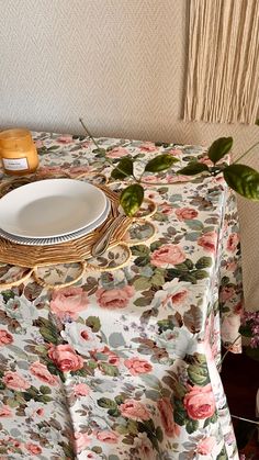 a table topped with a white plate next to a vase filled with flowers and greenery