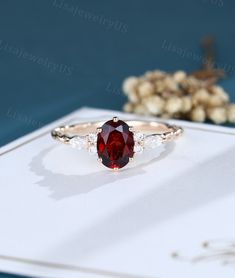 a ring with a large red stone surrounded by small white diamonds on top of a card