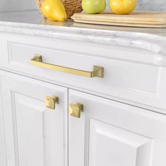 a kitchen with white cabinets and marble counter tops, gold handles on the pulls are brass