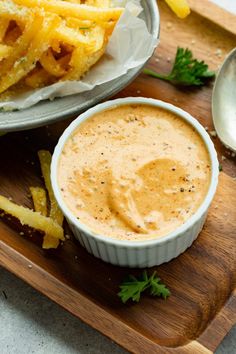 a wooden tray topped with french fries and dip