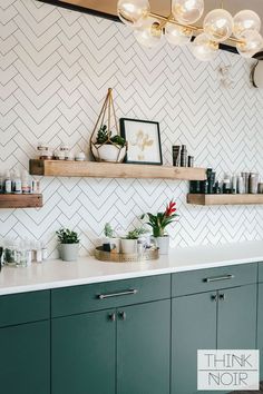 a kitchen with green cabinets and white tiled backsplash, hanging lights above the counter