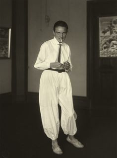 an old photo of a man in white pants and tie standing with his hands on his hips