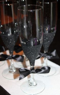 three wine glasses sitting on top of a table with black bows around the rims