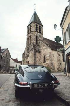 a car parked in front of a church on the side of a road next to tall buildings