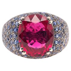 Year: 2000s Item Details: Ring Size: 6.75 Metal Type: 18K Gold with Tarnish [Hallmarked, and Tested] Weight: 10.2 grams Center Stone: GIA Report: 2235040270 Type: Tourmaline, (Purplish-Red) Shape: Oval Brilliant Step Cut Weight: Approximately 7.00ct Side Stones: Natural Sapphires, Blue, Round Brilliant, 1.00ct total weight Band Width: 5.5mm Condition: Excellent Luxury Multi-stone Pink Sapphire Ring, Luxury Pink Sapphire Ring With Gemstone Accents, Multicolor Ruby Ring For Formal Occasions, Luxury Pink Sapphire Ring For Formal Occasions, Formal Pink Sapphire Birthstone Ring, Multicolor Oval Sapphire Ring For Formal Occasions, Oval Multicolor Sapphire Ring For Formal Occasions, Luxury Multicolor Sapphire Ring For Formal Occasions, Formal Multi-stone Ruby Ring With Tourmaline