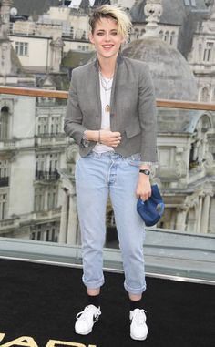 a woman standing on top of a black carpet in front of a cityscape