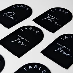 six black table numbers with white writing on them are arranged in the shape of hearts