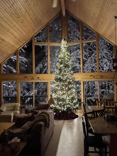 a living room with a christmas tree in the corner and large windows on both sides