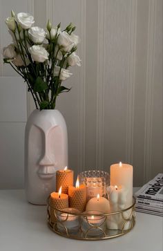 white roses in a vase and candles on a table