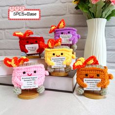 four small crocheted items sitting on top of a table next to a vase with flowers