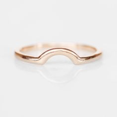 the gold curved ring is shown on a white background, it has a thin band that matches