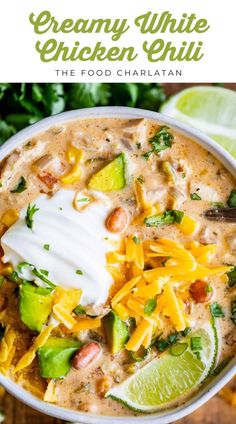 creamy white chicken chili in a bowl with sour cream on top and limes around it