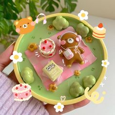 a hand holding a small plate with some food on it and teddy bear figurines