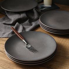 a table topped with plates and silverware on top of a wooden table next to a candle